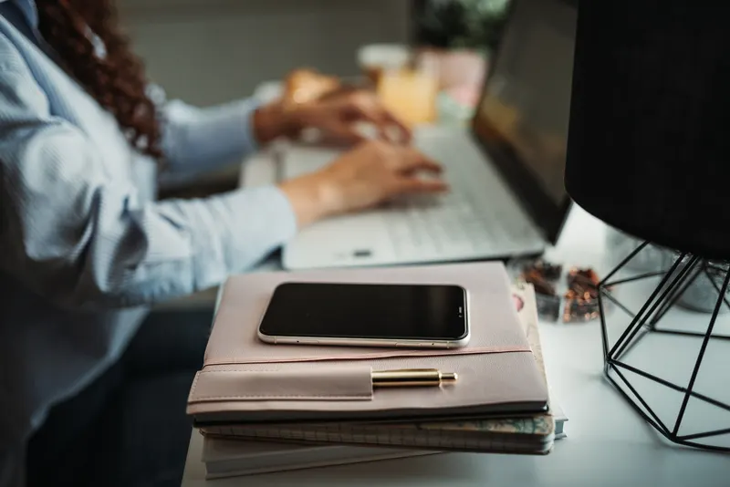 Open calendar application on a laptop next to a notebook on an office desk